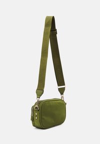 Piccolo borsa a tracolla verde oliva con cerniere e bottoni dorati, dotata di una larga tracolla regolabile impreziosita dal marchio "GUESS".