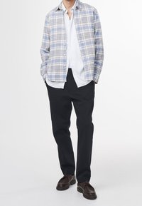 Kostkovaná košile ve světle modré a šedé barvě, nošená přes bílou košili s knoflíky, doplněná černými kalhotami a hnědými botami. Pohodlný střih, zapínání na knoflíky.