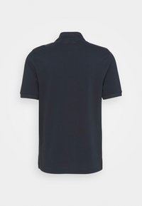 Polo à manches courtes bleu marine foncé vu de dos sur un fond clair uni.