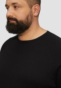 Zwarte crew neck t-shirt van katoen. Heeft een geribde halslijn en subtiele stikdetails op de schouders. Eenvoudig en aangesloten ontwerp.
