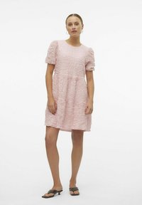 Rosa texturerad klänning med rund halsringning, puffärmar och en utsvängd kjol. Matcher med platta svarta sandaler.