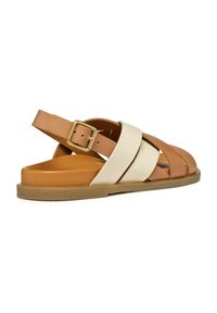 Sandalias de cuero marrón y crema con tiras entrelazadas, cierre de hebilla y suela plana y texturizada. Diseño moderno con un perfil minimalista.