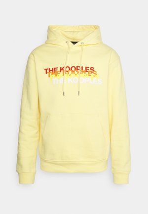 Vaaleankeltainen huppari etutaskulla ja "THE KOOPLES" -teksti painettuna rintaan punaisena, keltaisena ja valkoisena.