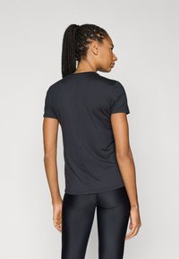 Μαύρο κοντομάνικο μπλουζάκι που προβάλλεται από πίσω, με απλό σχέδιο και ομαλή υφή, συνδυασμένο με μαύρα αθλητικά κολάν.