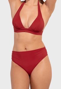 Bikini-Set mit tiefem V-Ausschnitt, Halterneck-Top und hochgeschnittenem Unterteil. Hergestellt aus einfarbig rotem Stoff mit weicher Textur und gerafftem Detail.