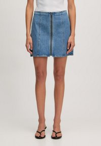 Jupe en denim bleu clair, avec une fermeture éclair centrale, un design à cinq poches et des coutures contrastantes le long des coutures. Taille plate.