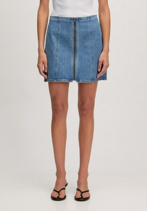 Denim mini skirt in light blue, featuring a central zipper, five-pocket design, and contrast stitching along the seams. Flat waistband.