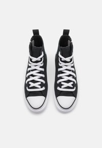 Černé kanvasové vysoké tenisky s bílými tkaničkami, bílou gumičkovou špičkou a poutkem na patě. Rovná podrážka s jemným prošíváním.