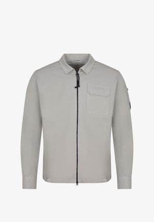 Camicia grigio chiaro a maniche lunghe con cerniera frontale, tasca sul petto con pattina e piccola tasca sulla manica sinistra.