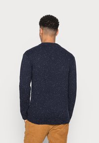 Navy-Pullover mit strukturierter Oberfläche, verziert mit farbigen Sprenkeln, geripptem Kragen, Bündchen und Saum; klassischer Schnitt mit langen Ärmeln.