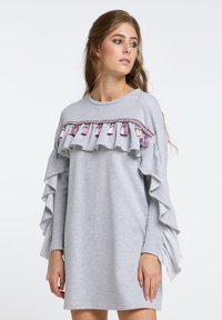 Graues Sweatshirtkleid mit Rüschenshirts, dekorativen Quasten in Pink und Weiß sowie einem runden Ausschnitt mit geflochtenem Sattel.
