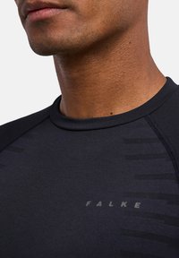 Czarna sportowa koszulka o dopasowanym kroju. Posiada okrągły dekolt, teksturowane paski po jednej stronie oraz detale z logo.