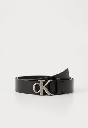 Black leather belt with a smooth texture, featuring a silver metal "CK" logo buckle. The belt is flat and neatly coiled.