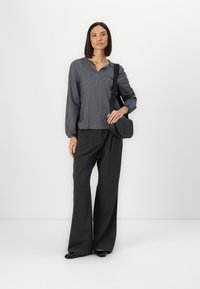 Black and white striped blouse with a v-neck, puffed sleeves, and gray, wide-leg trousers. Includes a black crossbody bag with logo.