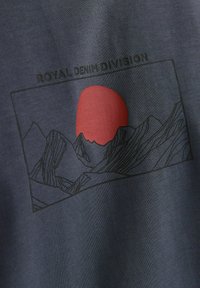 Tmavomodrý látkový vzor s grafickým designem zobrazujícím hory a červené slunce. Design je orámován černě a obsahuje text v horní části.