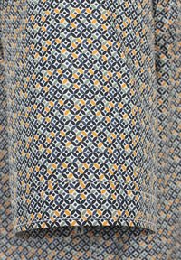 Koszula z krótkim rękawem z bawełny, w geometryczny wzór, w kolorach niebieskim, zielonym, pomarańczowym i białym, z prostym wykończeniem dołu.