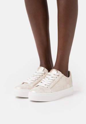 Lace-up sneakers in light beige suede with a textured pattern, white rubber sole, and metallic accents on the heel and eyelets.