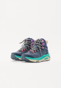 Hiking shoes in navy blue and teal, featuring a textured upper, colorful accents, and a rugged sole with a prominent Vibram logo.