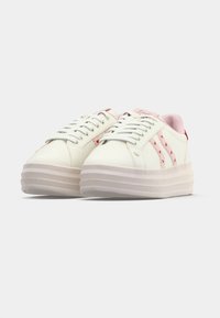 Baskets à plateforme blanches avec accents roses, présentant un design à lacets, des matériaux texturés et trois bandes décoratives sur le côté.