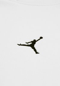 Tessuto bianco con una silhouette nera ricamata di una figura che salta e tiene un pallone da basket, caratteristico del branding atletico.