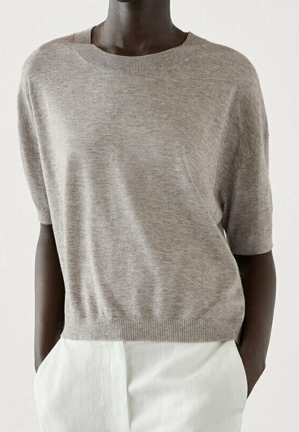 Vaaleanharmaa lyhythihainen neulepusero pehmeästä neulemateriaaliesta, pyöreä pääntie, rento malli, ribbaatut hihat ja helma, yhdistetty valkoisiin housuihin.