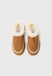 Brune svette slip-on tøfler med en kremfarget faux pelskant og beige sømdetaljer langs kantene. Størrelsesetikett synlig inni.