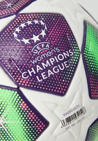 Nærbillede af en UEFA Women's Champions League fodboldpanel med et design i lilla, grøn og rosa prikker og stregkode på en hvid tekstureret overflade.