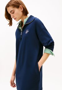 Φόρεμα φερμουάρ σε ναυτικό μπλε χρώμα με γιακά με πράσινες ρίγες· διαθέτει πλαϊνέ�ς τσέπες και κεντημένο λογότυπο στο στήθος· άνετη γραμμή.