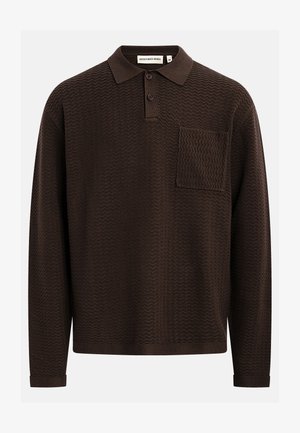 Brun långärmad pikétröja med ett texturerat sicksackmönster, med en knapplist med tre knappar och en bröstficka. Tillverkad av stickat tyg.