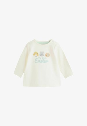 Chemise blanche en coton à manches longues avec des motifs d'animaux brodés (poussin, lapin, abeille) et le texte "ma première Pâques" en couleurs douces.