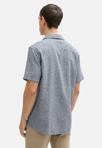 Kurzärmliges blaues kariertes Hemd, mit Kragen, aus strukturiertem Stoff. Die Rückansicht zeigt einen geraden Schnitt und vertikale Nahtdetails.