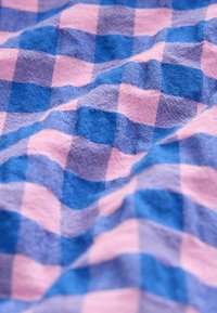 Blauw- en roze geruit stof, met een zachte textuur en geweven patroon met afwisselende blokjes van effen kleur en gestructureerd weefsel.