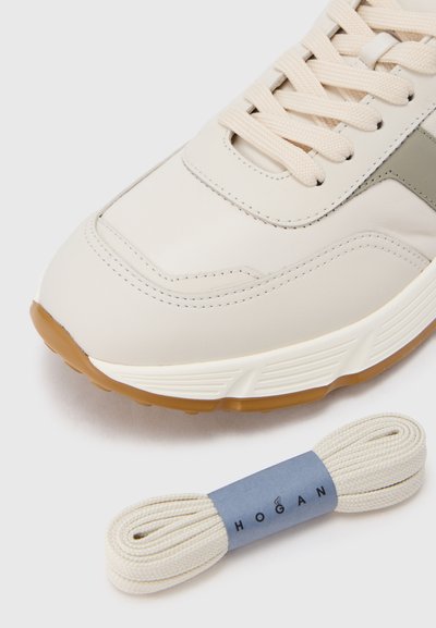 Baskets en cuir beige avec une tige texturée, un bout arrondi, une bande contrastante grise et une semelle en caoutchouc naturel. Comprend des lacets beiges.