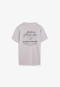 Camiseta de algodón de color rosa claro con mangas cortas. La parte posterior presenta texto impreso en negro y un gráfico, detallando "Scalpers Lounge Bar" y la información de servicio.