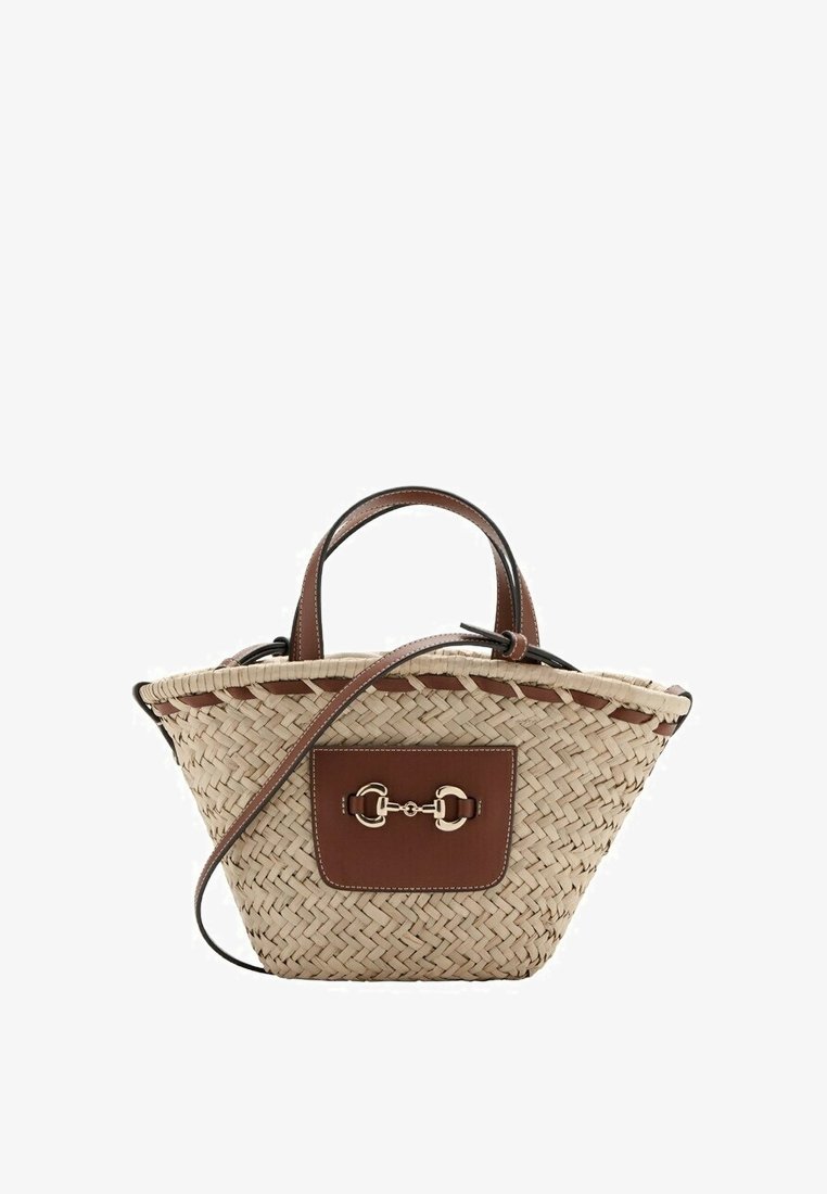 Sac à main en paille tressée avec poignées en cuir marron, patch avant et détail mors en argent, avec une longue bandoulière en cuir réglable.