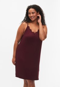 Camicetta bordeaux con rifiniture in pizzo, spalline regolabili e vestibilità comoda. Texture liscia, design al ginocchio e spacchetti laterali per maggiore comfort.