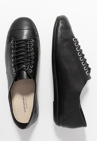 Čierne kožené tenisky s okrúhlou špičkou, viazaním vpredu a kovovými očkami. Hladká štruktúra s jemným leskom a nízkym profilom.