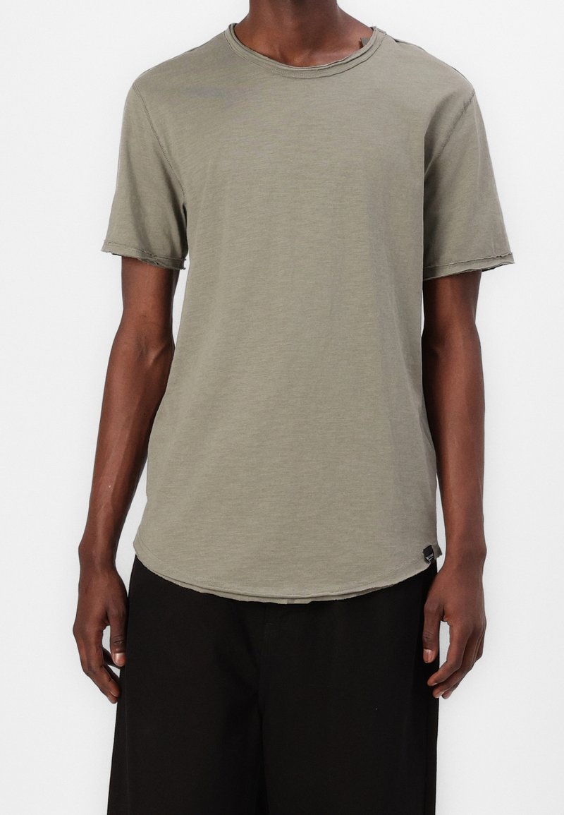 Olijfgroene t-shirt met korte mouwen, ronde hals, rafelige zoom en een ontspannen pasvorm. Zachte textuur, ontworpen voor casual gebruik.