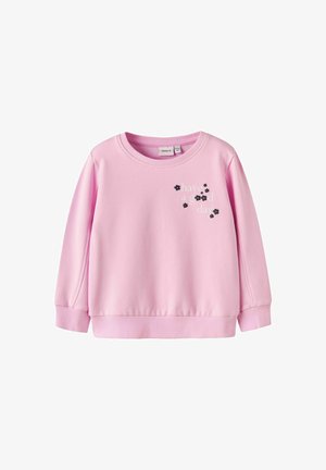 Jasnoróżowy sweter z długim rękawem, z prążkowanymi mankietami i dołem, z nadrukowanym napisem "miłego dnia" oraz małymi czarnymi akcentami w postaci kwiatów.