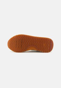 Semelle en caoutchouc avec un motif ondulé, principalement orange. Présente un bout arrondi et une surface lisse et texturée pour l'adhérence.