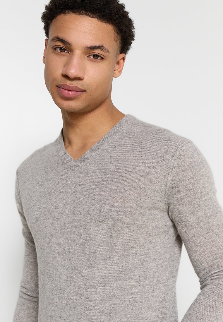 Grauer V-Ausschnitt-Pullover aus einem weichen, leichten Strickstoff. Verfügt über lange Ärmel und ein tailliertes Design, mit einer glatten Textur und minimalen Details.