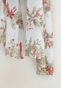 Bílá látka s květinovým vzorem ostrolistových listů, červených bobulí a červených stuh se zelenými akcenty, jemně se zavěšená.