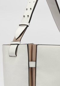 Sac à main en cuir blanc au design structuré, intérieur beige contrasté, anse supérieure et bandoulière réglable avec des accents en métal argenté.