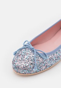 Ballerine bleue scintillante avec des paillettes roses et argentées, bordure bleu clair, nœud bleu clair et doublure intérieure rose.