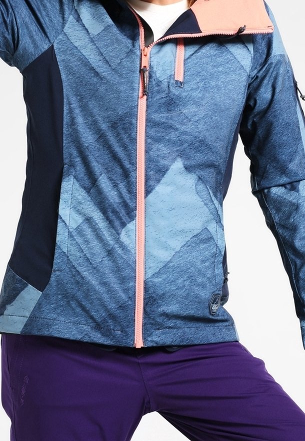 Giacca blu e navy con motivo, con zip rosa, caratterizzata da un alto colletto e tasche, abbinata a pantaloni viola.