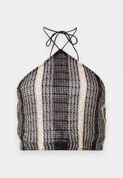 Crop top à sequins noir et blanc, style halter avec liens à nouer au cou et motif à rayures verticales.
