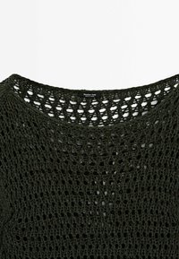 Col encolure et épaules d'un pull vert foncé à mailles ouvertes avec une petite étiquette "Massimo Dutti" centrée à l'intérieur du col.