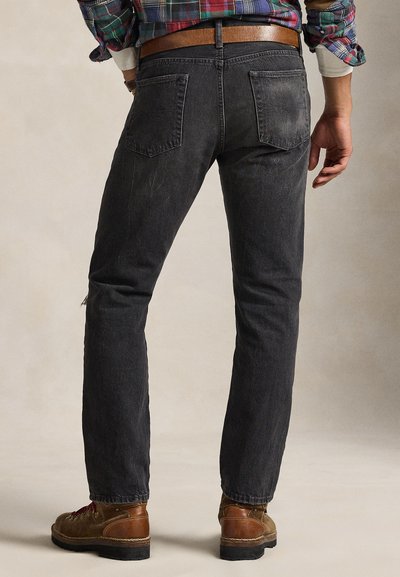 Σκούρα γκρι τζιν παντελόνια από ντένιμ με ίσια γραμμή στο πόδι, διαθέτουν πίσω τσέπες και ελαφριά φθορά. Φορεμένα με καφέ μπότες και καρό πουκάμισο.