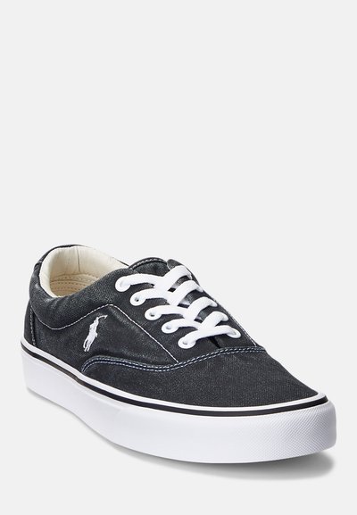 Σκούρες γκρι τζιν αθλητικά παπούτσια με λευκές δέστρες και ραφές. Διαθέτουν λευκή καουτσούκ σόλα και ένα μικρό λογότυπο στο πλάι.