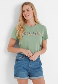 Green cotton t-shirt featuring floral "BLOOM" lettering, paired with blue denim shorts with rolled cuffs. Simple design and relaxed fit.